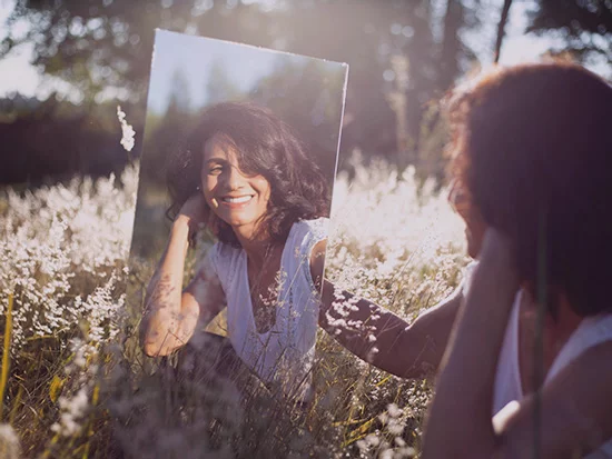 A person holding a mirror that reflects their positive self-concept.