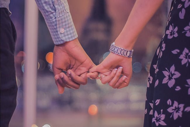 A close-up of a couple holding hands, symbolizing manifesting someone to like you back.